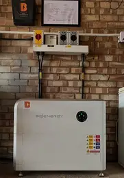 A Sigenergy storage unit on a brick wall, connected with cables and switches