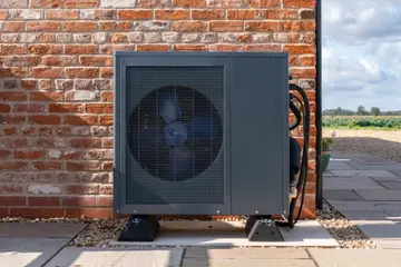 Outdoor heat pump unit installed against a wall