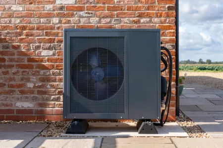 Outdoor heat pump unit installed against a wall