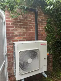 Toshiba outdoor air conditioning unit installed on a brick exterior wall.