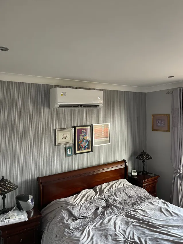 A wall-mounted air conditioning unit neatly installed in a customer's bedroom