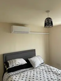 A discreet wall-mounted split air conditioning unit in a modern bedroom
